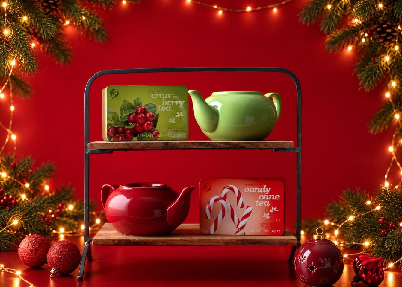 Adagio cranberry and candy cane tea tins with red and green teapots on a shelf, framed by evergreen string lights